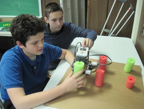 students measuring a tree trunk with a Lego caliper