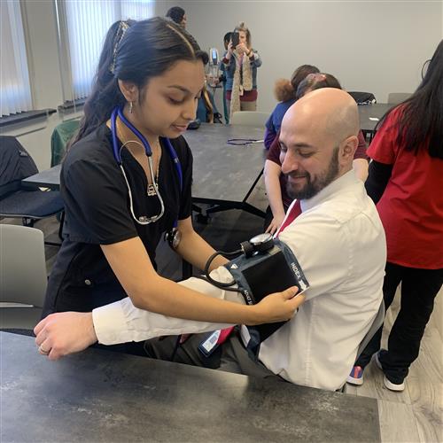 A female student enrolled in the CTE medical cluster takes Neal Brokman's blood pressure.