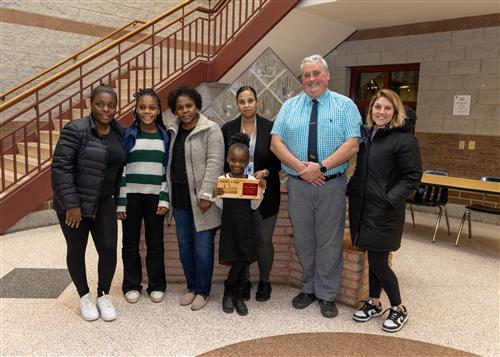 Grover Cleveland Stairclimber Faida Malango posing with her plaque, family members, and Assistant Principal Dennis Carner.