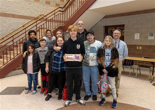 Patrick J. DiPaolo Stairclimber Brandon Hope posing with his plaque, family members, & Assistant Principal Dr. Eric Sandberg.