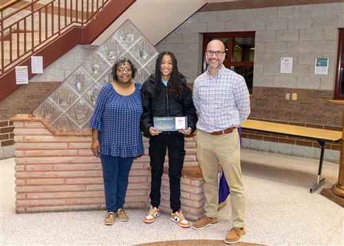 Ja'Ryiah Green, Erie High's November Stairclimber, poses with her plaque, a family member, and Principal Don Orlando.