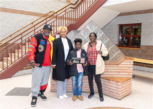 Carion Thompson, Eagle's Nest's November Stairclimber, poses with his plaque and family members.