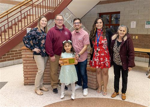 McKinley's March Stairclimber, Viviana Claudio, posing with her plaque, family members and school staff.