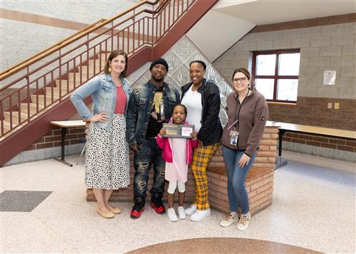 Jazariona Petty, Connell Elementary's April Stairclimber, poses with her plaque and family members and school staff.