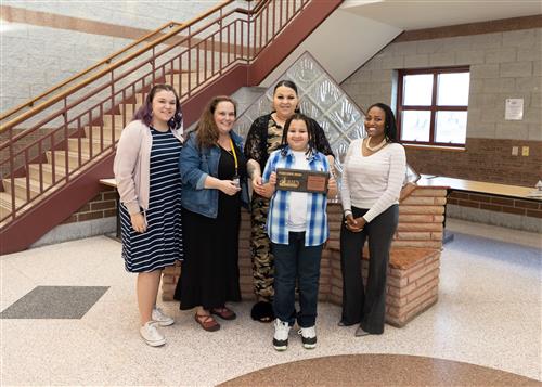 Deandre Rockett, Grover Cleveland Elementary's April Stairclimber, poses with his plaque, family members and principal.