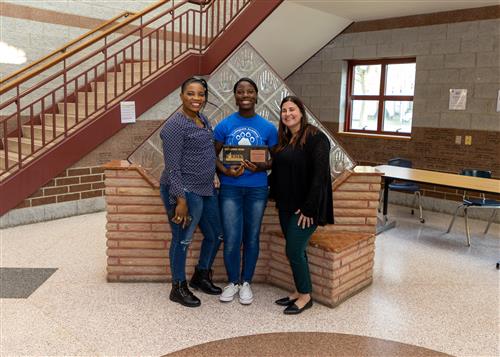 Rebecca Kendema, Collegiate Academy's May 2023 Stairclimber, poses with a family member and Associate Dean Church-Rivera.