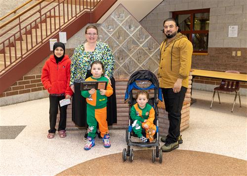 Kayan Al-Ghayeb, Lincoln's December Stairclimber, poses with his plaque, family members, and Principal Huffman.