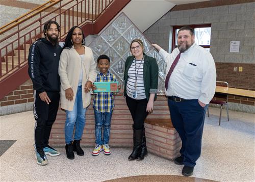 Zayvion Nixon, JoAnna Connell's March Stairclimber, poses with his plaque, family members and school staff.