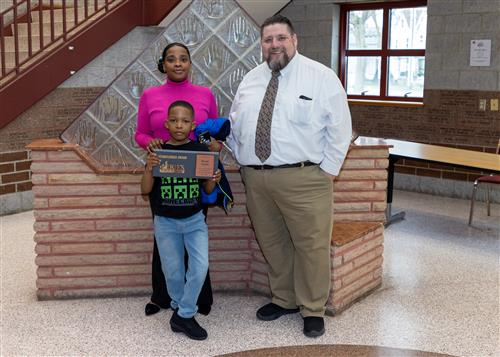 David Vactor, JoAnna Connell Elementary's April Stairclimber, poses with his plaque, a family member and Principal Causgrove.