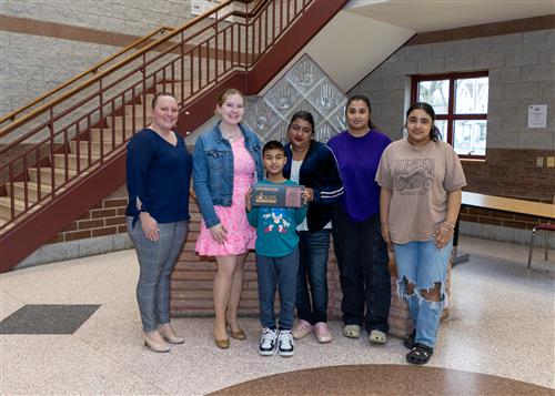 Ashish Khadka, Grover Cleveland Elementary's April Stairclimber, poses with his plaque, family members and school staff.