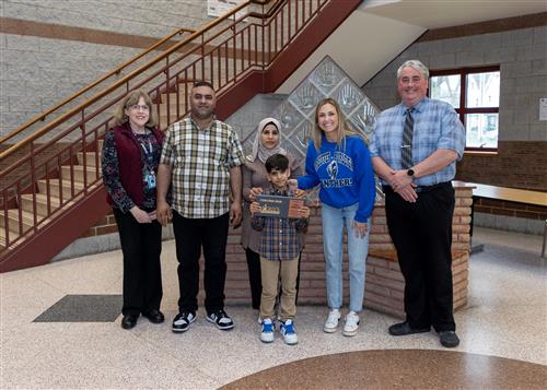 Ashish Khadka, Pfeiffer-Burleigh's April Stairclimber, poses with his plaque, family and school staff.