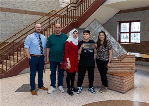 Mohammed Shekho, East Middle School's April Stairclimber, poses this his plaque, family members, and school staff.