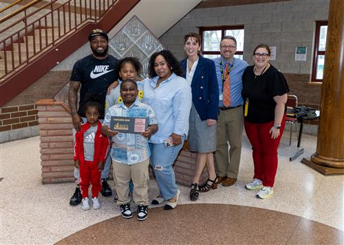 Santana Hollingsworth, Patrick J. DiPaolo's April Stairclimber, poses with his plaque, family members and school staff.