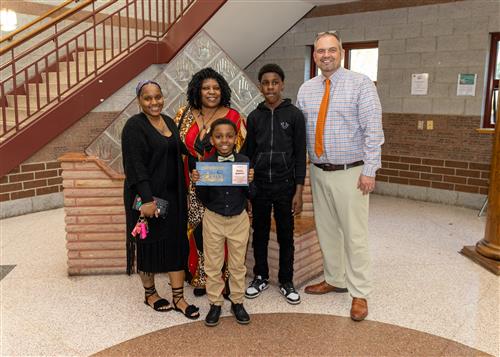 Darius Gambill, Jefferson Elementary's May Stairclimber, poses with his plaque, family members, and Principal Jeff Boam.