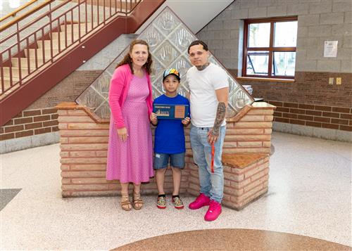 Eric Ortiz Portalatin, Perry Elementary School's May Stairclimber, poses with his plaque, a family member & Principal Gunns.