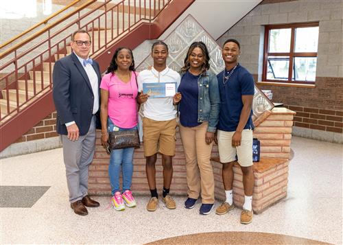 Dae'Waun Henderson, Collegiate Academy's May Stairclimber, poses with his plaque, family members, and Dean Jim Vieira.