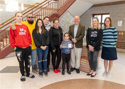 Isabella Burton, Harding Elementary's May Stairclimber, poses with her plaque, family members, and school staff.