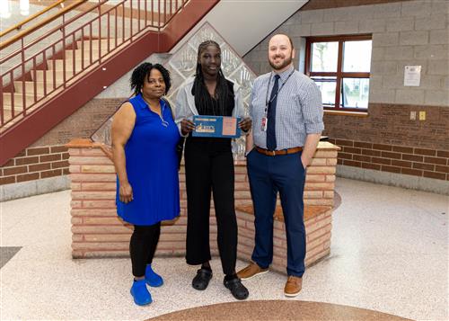 Angeth Guem, East Middle School's May Stairclimber, poses with her plaque, a family member, and Principal Matt Koval.