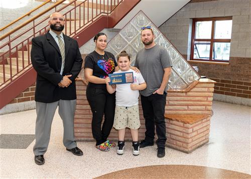 Joshua "Josh" Farnham, Grover Cleveland's May Stairclimber, poses with his plaque, family members, & DEI Coordinator Nickson.