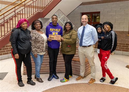 Jerrico Beason, Erie High's November 2022 Stairclimber, standing with family and Principal Don Orlando.