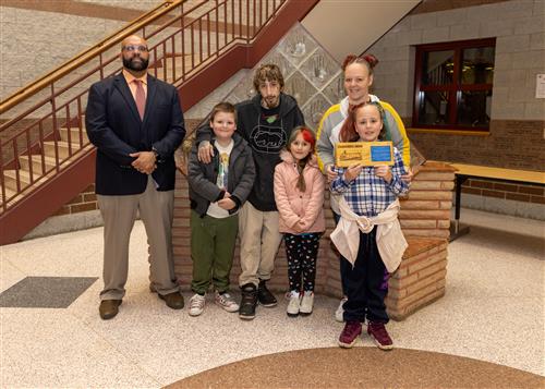 Faith Czuwara, Pfeiffer-Burleigh's December Stairclimber, posing with her plaque, family members, and DEI Coord. Ken Nickson.