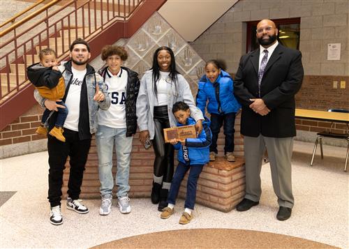 Manuel DeJesus, Eagle Nest's January 2023 Stairclimber, poses with his plaque with family members and DEI Coord. Ken Nickson.