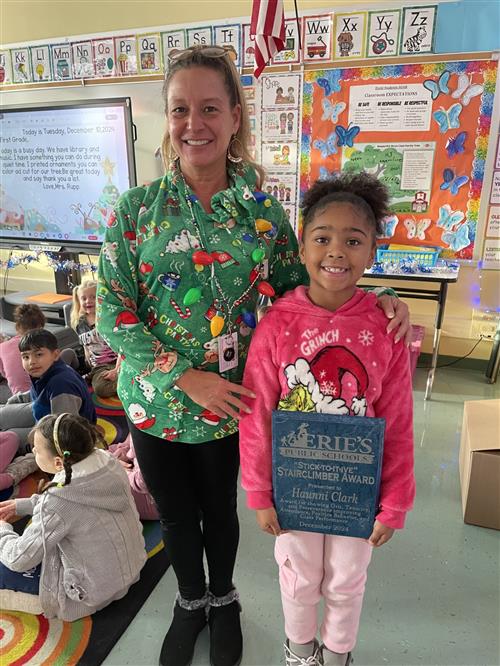 Haunni Clark, Diehl Elementary's December Stairclimber, poses with her teacher and plaque.