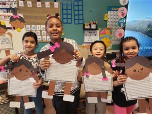 Photo of four students holding up written projects focusing on Ruby Bridges.