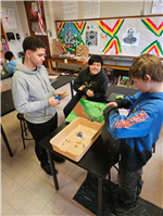 Three students working together in groups making farms/gardens to understand the work of George Washington Carver.