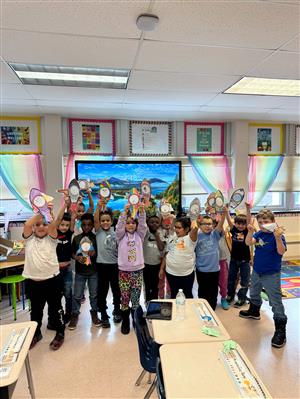 A group of students, each student holding up a cutout of a rocketship.