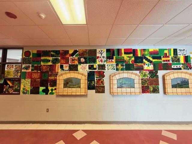 Image of many student-created artworks displayed in the hallway of East Middle. The art is in the style of Basquiat.